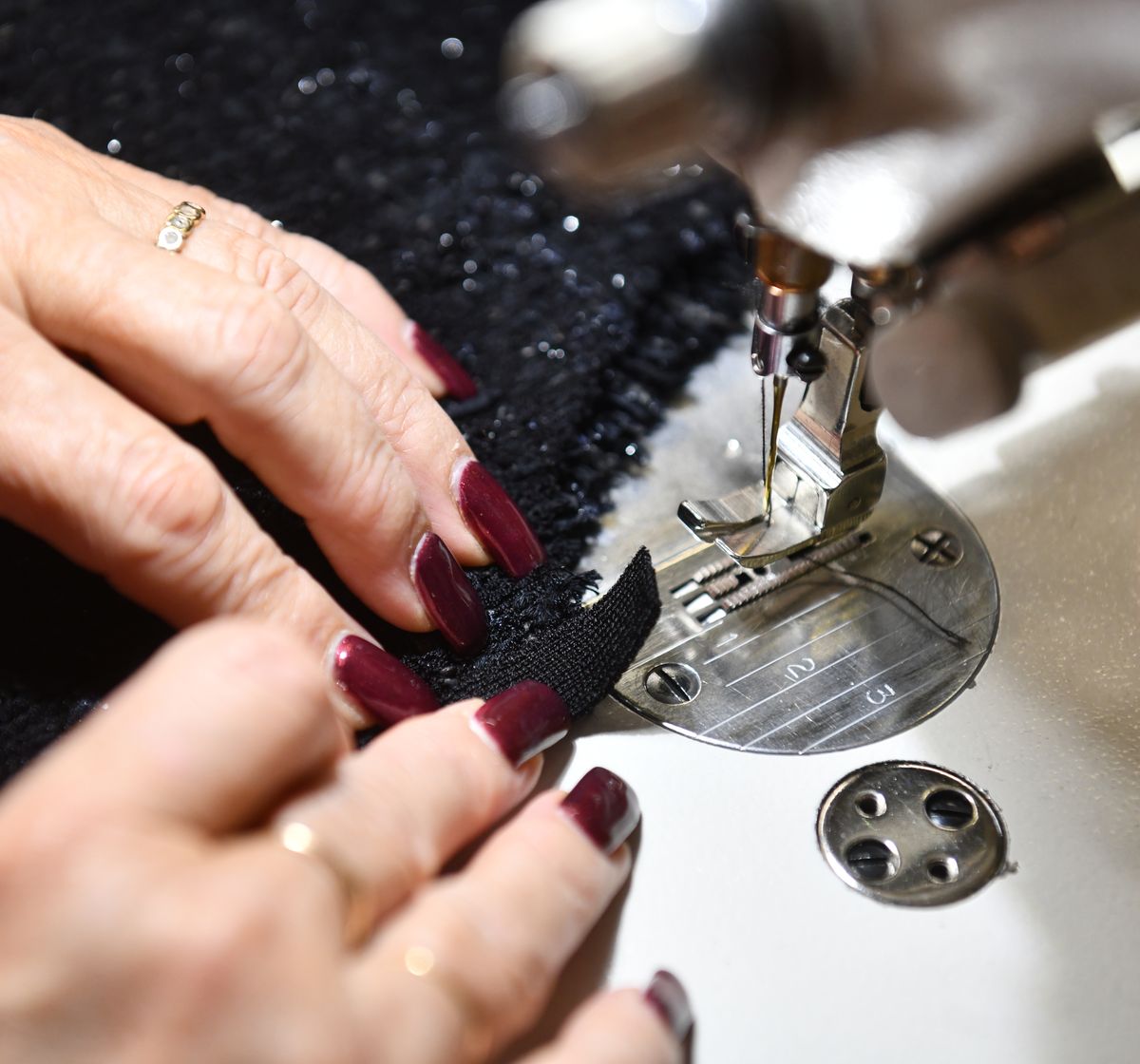 Mains d'une mécanicienne Servistyl piquant une pièce effet tweed à la machine